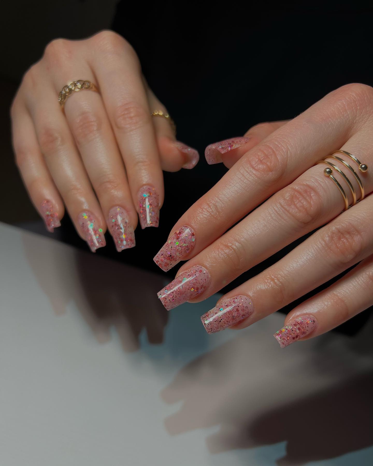 Pink glitter coffin nails on a reflective surface